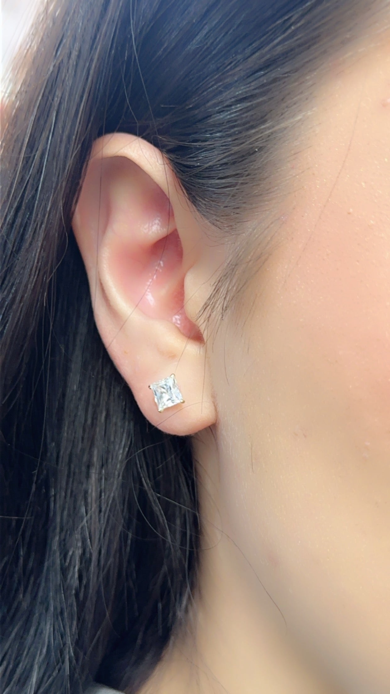 Pair of 14K yellow gold square moissanite studs on display