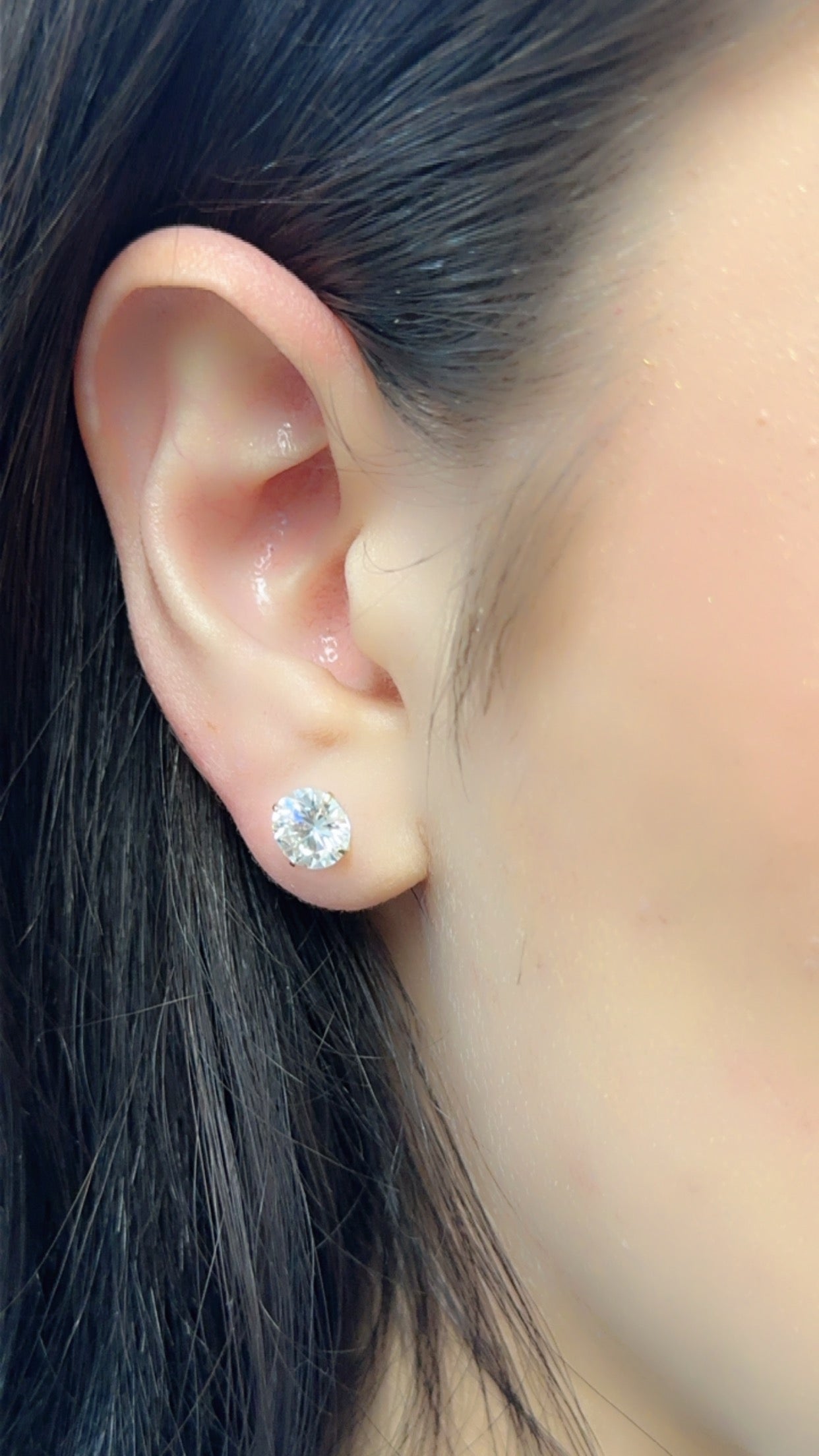 Pair of 14K yellow gold round moissanite studs on display